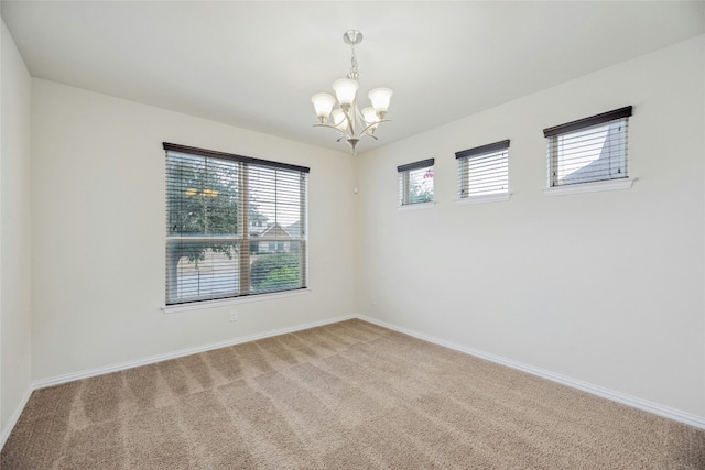 carpeted empty room featuring baseboards and a notable chandelier