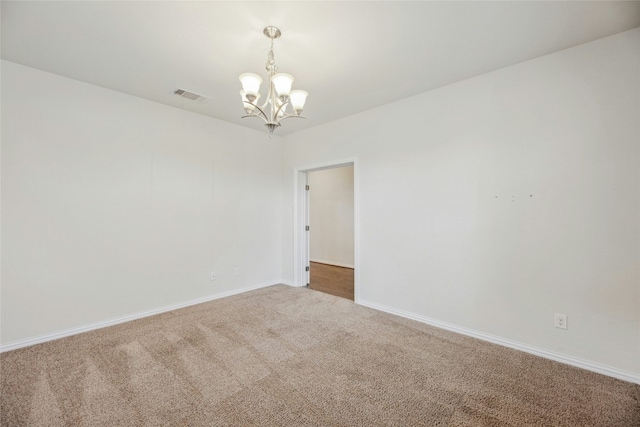 carpeted empty room with baseboards, visible vents, and an inviting chandelier