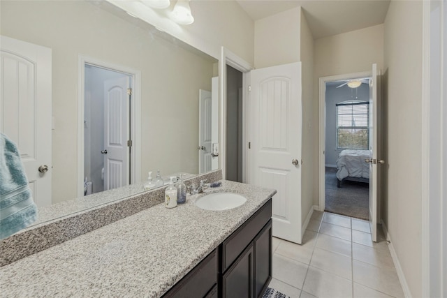 ensuite bathroom with tile patterned flooring, connected bathroom, vanity, and baseboards