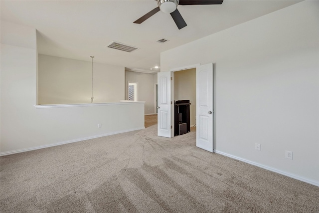 spare room featuring light colored carpet, visible vents, ceiling fan, and baseboards