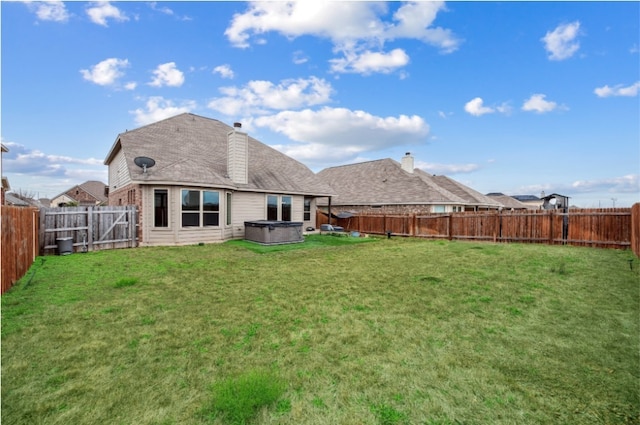 rear view of property featuring a yard, a fenced backyard, and a hot tub