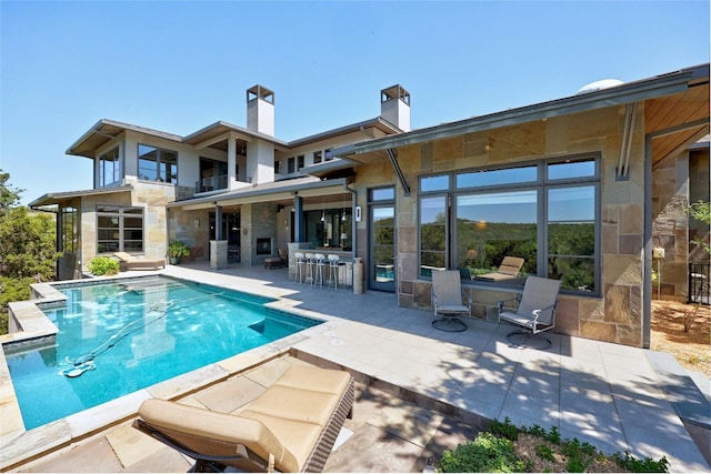 702 Crystal Mountain Dr, Austin, TX 78733 - rear view of house featuring a patio, an outdoor pool, stone siding, and a balcony