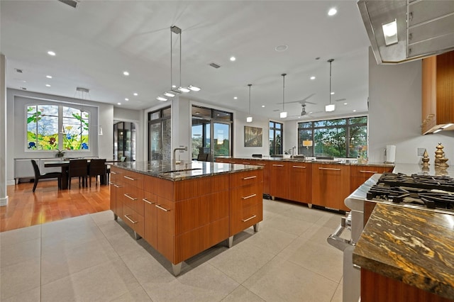 702 Crystal Mountain Dr, Austin, TX 78733 - kitchen with modern cabinets, brown cabinets, plenty of natural light, dark stone countertops, and recessed lighting