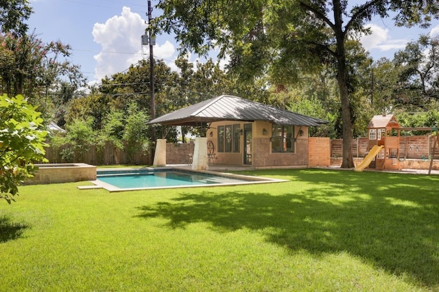 rear view of property featuring a yard, a playground, an outdoor structure, and a fenced in pool