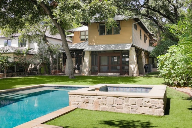 back of house featuring a lawn and a pool with hot tub