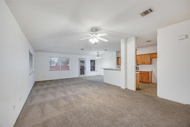 unfurnished living room with light colored carpet and ceiling fan with notable chandelier