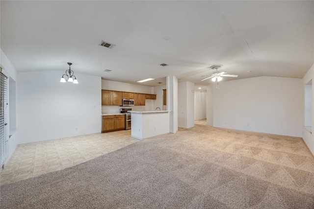 unfurnished living room featuring vaulted ceiling, light colored carpet, and ceiling fan with notable chandelier