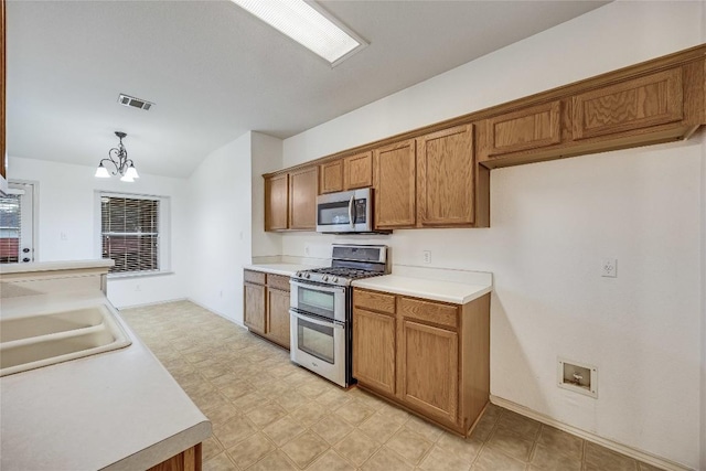 3580 Rock Shelf Ln, Round Rock, TX 78681 - kitchen featuring appliances with stainless steel finishes, brown cabinetry, a chandelier, light flooring, and hanging light fixtures
