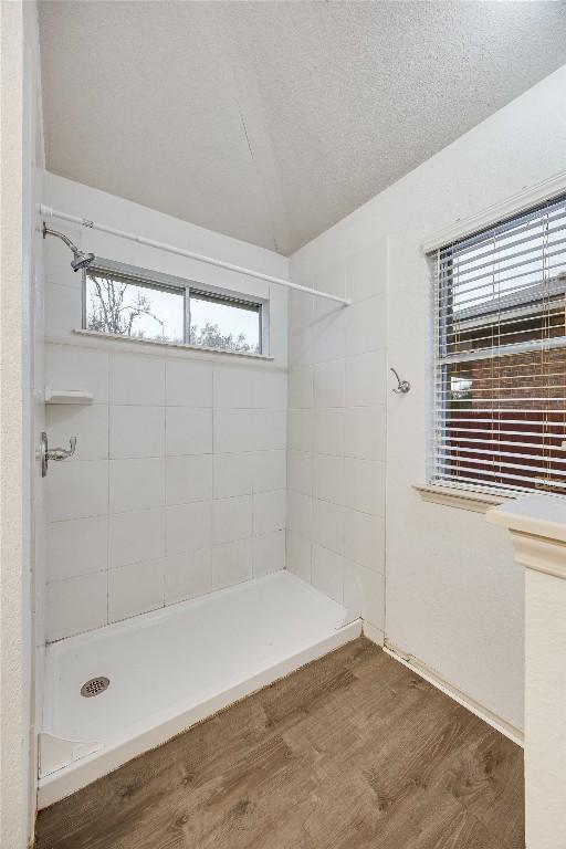 bathroom featuring hardwood / wood-style floors, tiled shower, and a textured ceiling