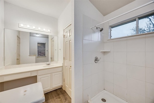 bathroom featuring hardwood / wood-style flooring, vanity, and tiled shower