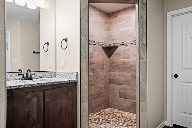 bathroom featuring tiled shower and vanity