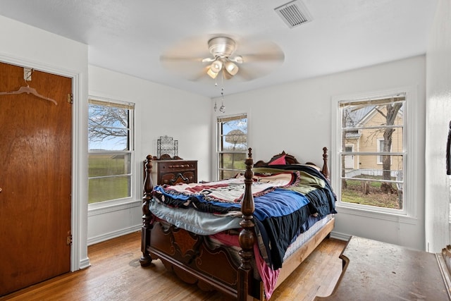 bedroom featuring multiple windows, wood-type flooring, and ceiling fan