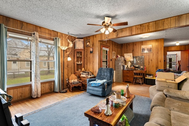 living room with a textured ceiling, wood walls, and light hardwood / wood-style floors