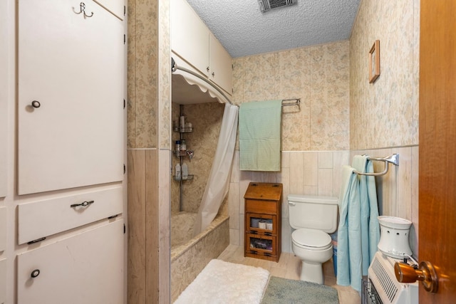 bathroom featuring shower / bath combo, tile patterned flooring, toilet, tile walls, and a textured ceiling