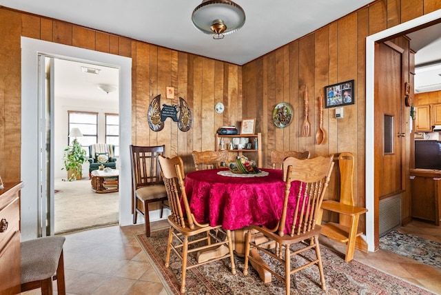 dining room featuring light tile patterned flooring and wood walls