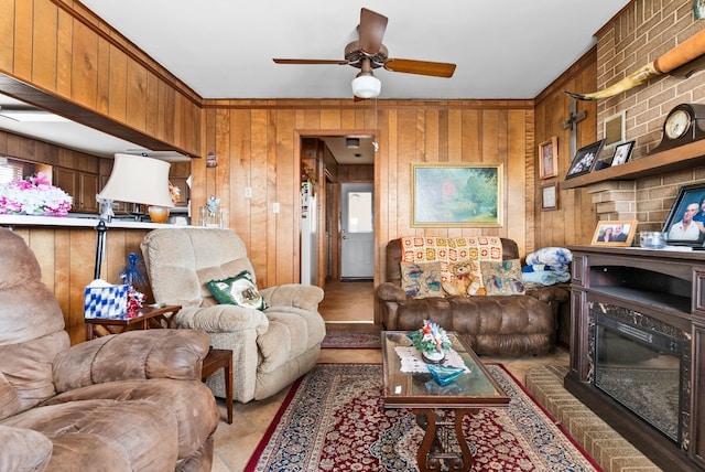 living room featuring ceiling fan, a brick fireplace, and wooden walls