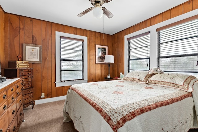 bedroom featuring ceiling fan, wood walls, and light colored carpet