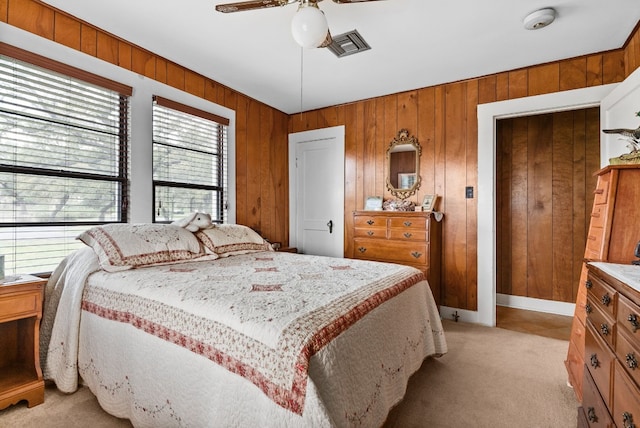 carpeted bedroom featuring ceiling fan and wooden walls