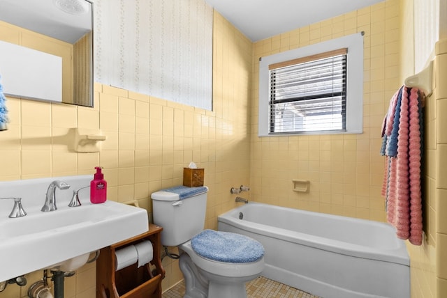 bathroom with a tub to relax in, tile patterned flooring, sink, toilet, and tile walls