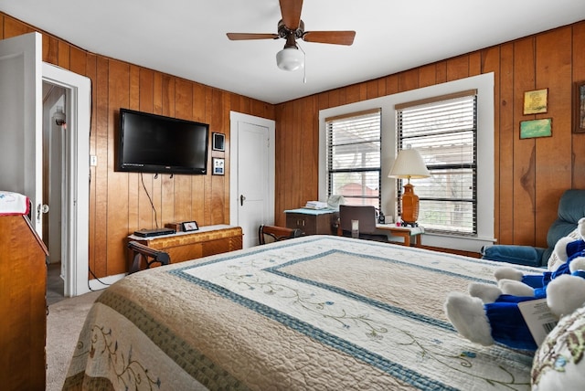 carpeted bedroom featuring ceiling fan and wooden walls