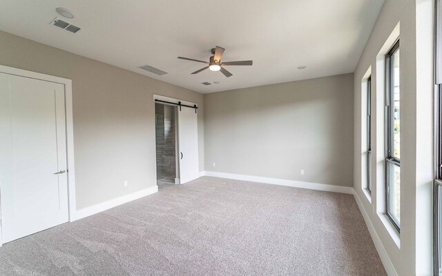 1002 Barrie Dr, Austin, TX 78734 - unfurnished bedroom with carpet, a barn door, multiple windows, and a ceiling fan