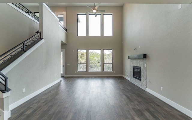 1002 Barrie Dr, Austin, TX 78734 - unfurnished living room featuring a ceiling fan, a high end fireplace, dark wood finished floors, stairs, and a high ceiling
