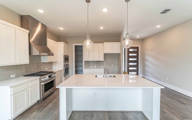 1002 Barrie Dr, Austin, TX 78734 - kitchen featuring stainless steel appliances, wall chimney range hood, wood finished floors, an island with sink, and recessed lighting
