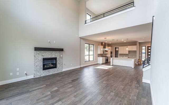 1002 Barrie Dr, Austin, TX 78734 - unfurnished living room with dark wood-type flooring, a tiled fireplace, and a high ceiling