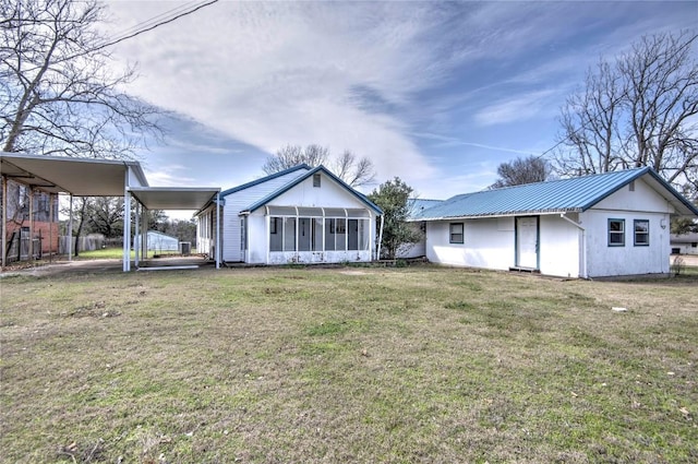 rear view of property with a lawn, a sunroom, and a carport