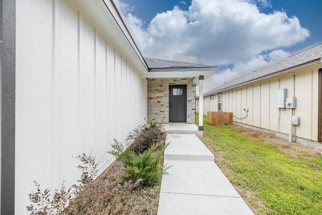 property entrance featuring board and batten siding, stone siding, and a lawn