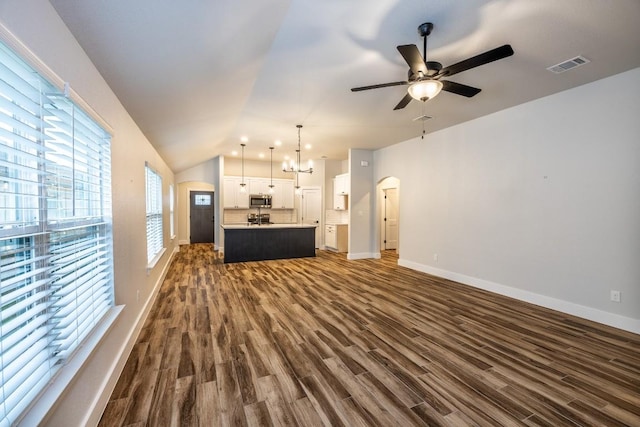 unfurnished living room with visible vents, arched walkways, lofted ceiling, dark wood-style flooring, and ceiling fan with notable chandelier