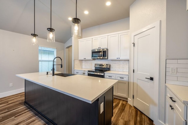 kitchen with appliances with stainless steel finishes, a kitchen island with sink, light countertops, and a sink