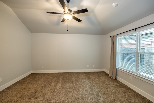 carpeted empty room featuring vaulted ceiling, ceiling fan, and baseboards