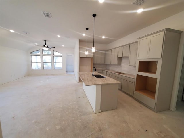 kitchen with hanging light fixtures, sink, vaulted ceiling, gray cabinets, and light stone counters