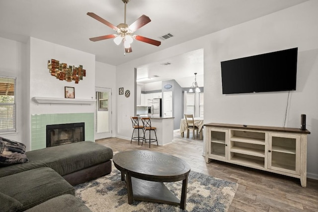 living room featuring a fireplace, ceiling fan, and wood-type flooring