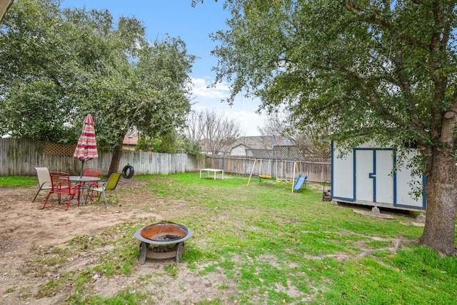 view of yard with a playground, a storage shed, and a fire pit