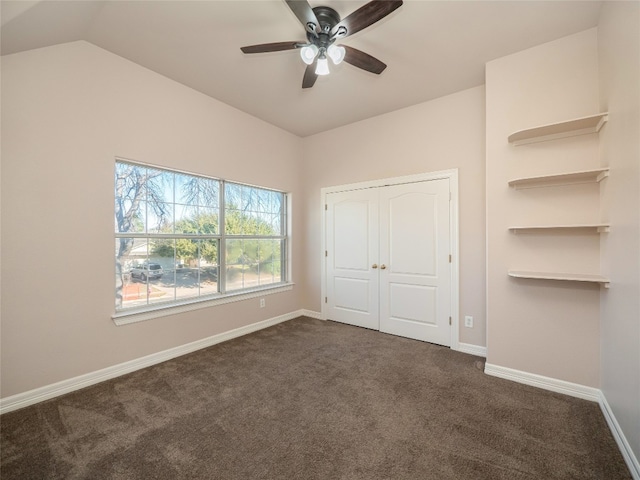 unfurnished bedroom featuring lofted ceiling, ceiling fan, dark colored carpet, and a closet