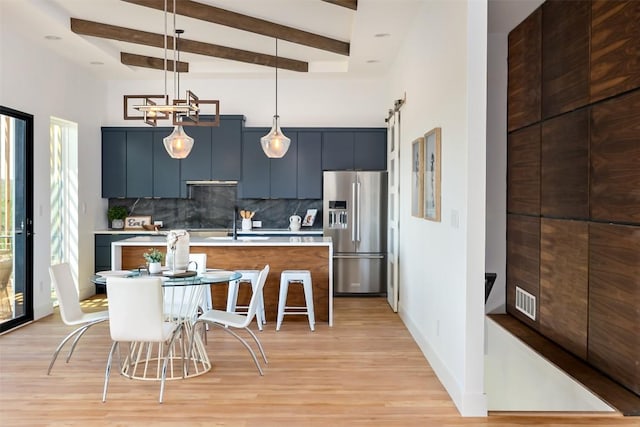 kitchen with a kitchen island, tasteful backsplash, decorative light fixtures, and stainless steel refrigerator with ice dispenser