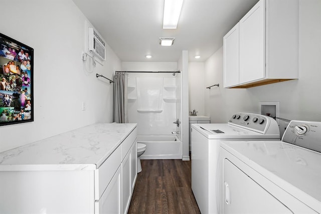 washroom with sink, a wall mounted AC, dark hardwood / wood-style flooring, and washer and clothes dryer