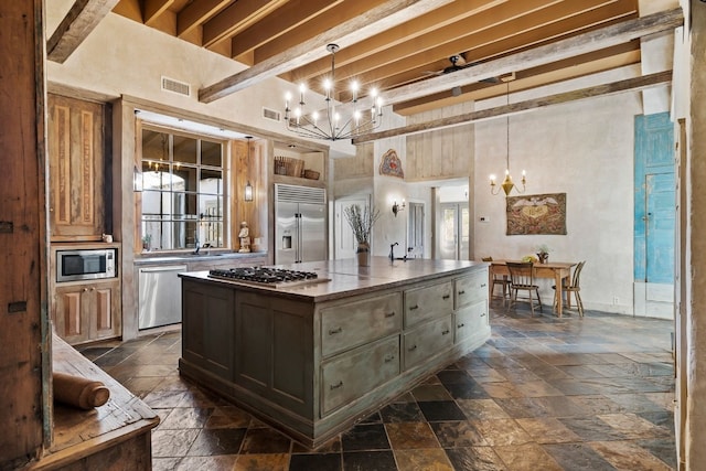 kitchen with built in appliances, a chandelier, stone tile floors, a center island, and dark countertops