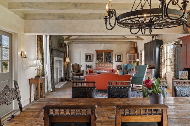 interior space with an inviting chandelier, plenty of natural light, beamed ceiling, and wood finished floors