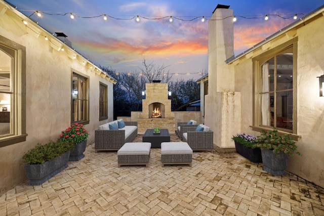 patio terrace at dusk with an outdoor living space with a fireplace