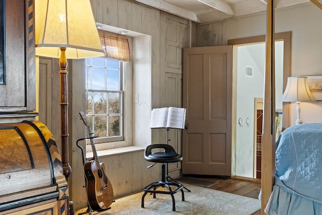 bedroom with wood finished floors, visible vents, and wooden walls