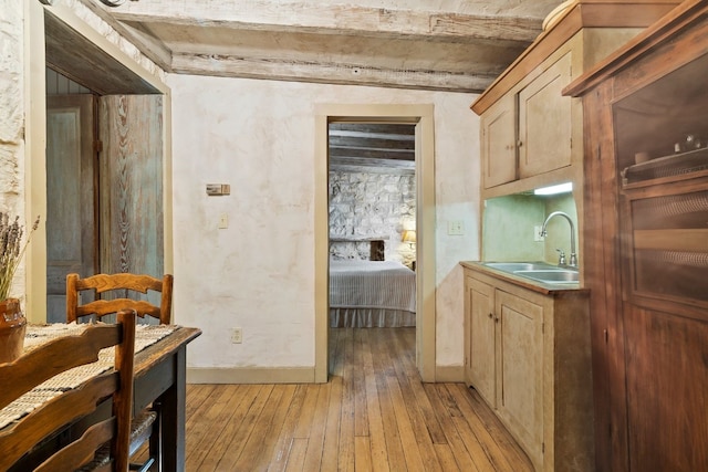 kitchen with light wood finished floors, baseboards, light countertops, light brown cabinetry, and a sink