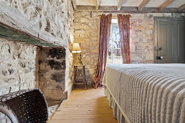 bedroom with beamed ceiling and light wood-style flooring