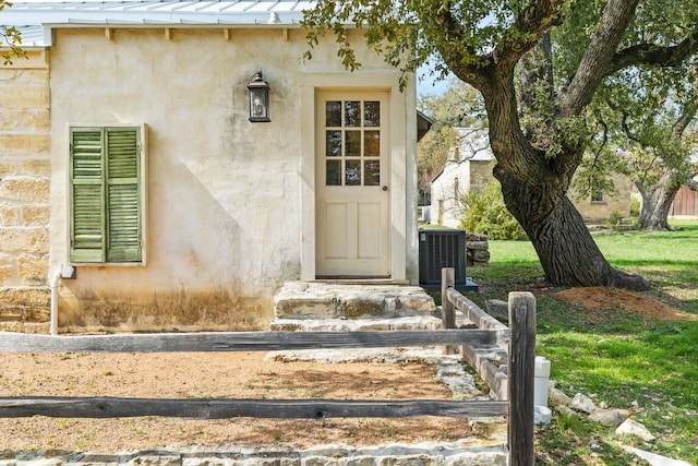 entrance to property featuring central AC, metal roof, a standing seam roof, and visible vents