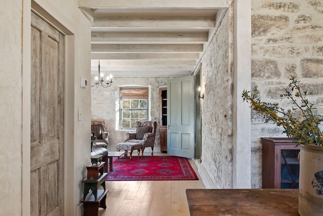 hall with beamed ceiling, wood finished floors, and a notable chandelier