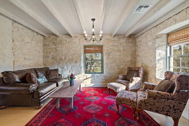 living area featuring a wealth of natural light, beam ceiling, and visible vents