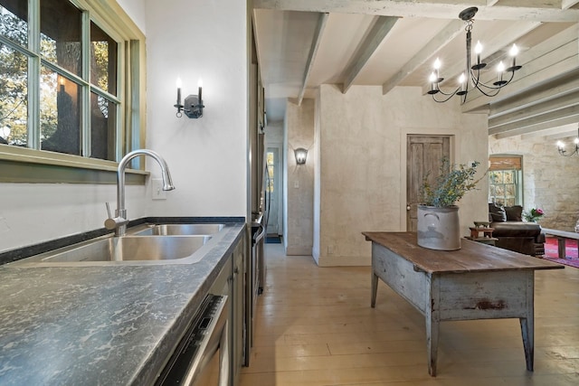 kitchen with a sink, beam ceiling, light wood finished floors, dark countertops, and decorative light fixtures