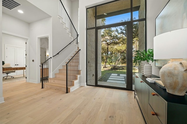 entryway featuring light hardwood / wood-style floors and a towering ceiling